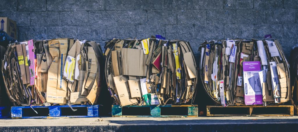 Three bundles of recyclable cardboard ready for shipment.